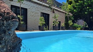 A swimming pool with clear blue water, surrounded by potted plants and a building with large windows. - Pousada Toa Toa Em Pipa (Tibau do Sul)