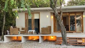 A modern house with a covered outdoor seating area, a wooden bench, and a tree. - ROSARIO ISLANDS, BEACH HOUSE (Cartagena de Indias)