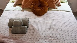 Una cama con cabecera de madera, varios almohadones y una colcha.