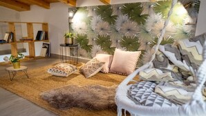 Una sala de estar acogedora con un sofá, cojines estampados, un tapete mullido y una estantería.