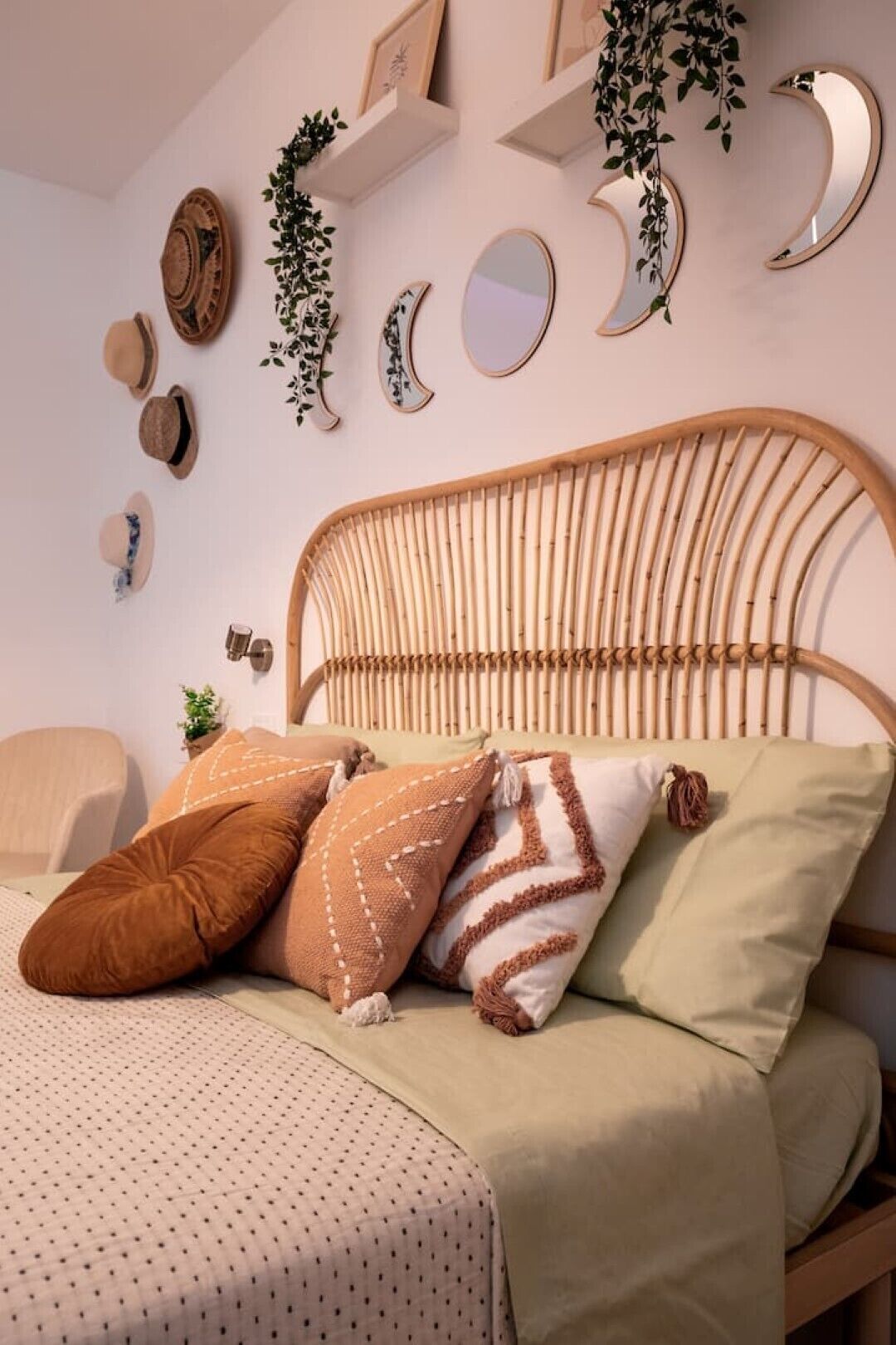 Ein Bett mit einem gewobenen Kopfteil, mehreren Kissen und einer Wand mit dekorativen Spiegeln und Pflanzen.