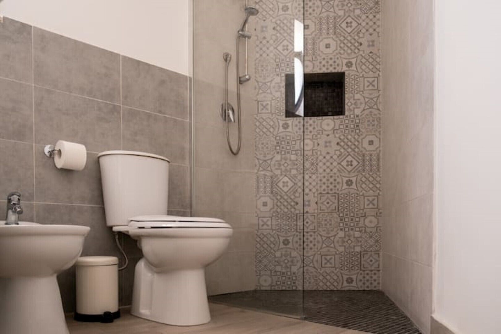 Et badeværelse med toilet, bidet og bruser.