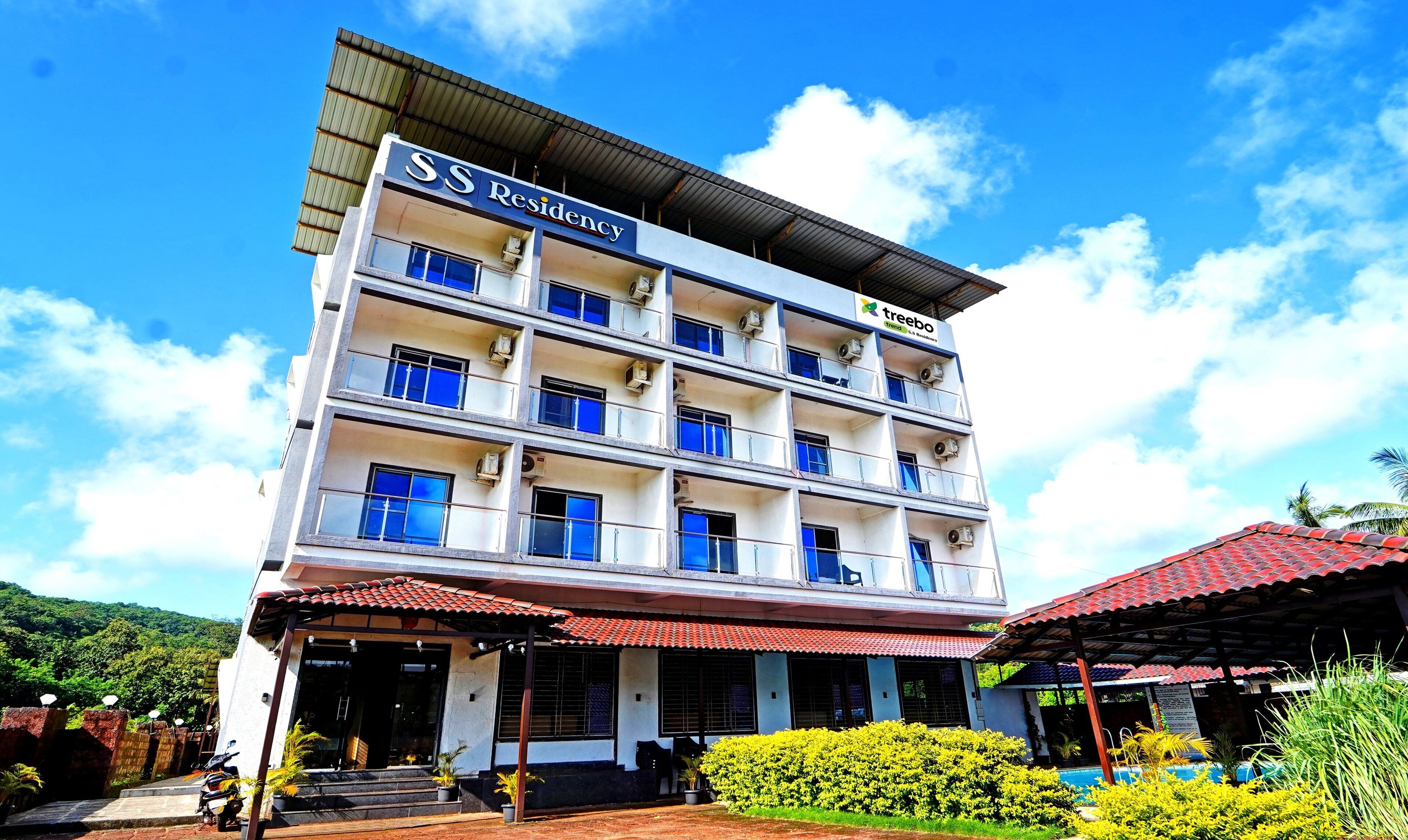 A multi-story residential building with balconies, air conditioning units, and a sign indicating it is a 'SS Residency'.