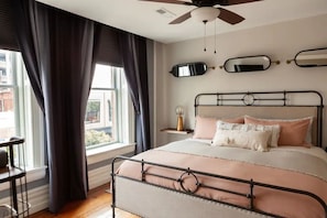 Un dormitorio con cama, ventilador de techo y ventana con cortinas.