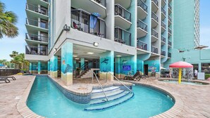 A hotel with a swimming pool, multiple balconies, and a view of the ocean. - Compass Cove Mariner Tower 624 - Ocean Front Condo - Pools, Lazy River, Hot Tub (Myrtle Beach)