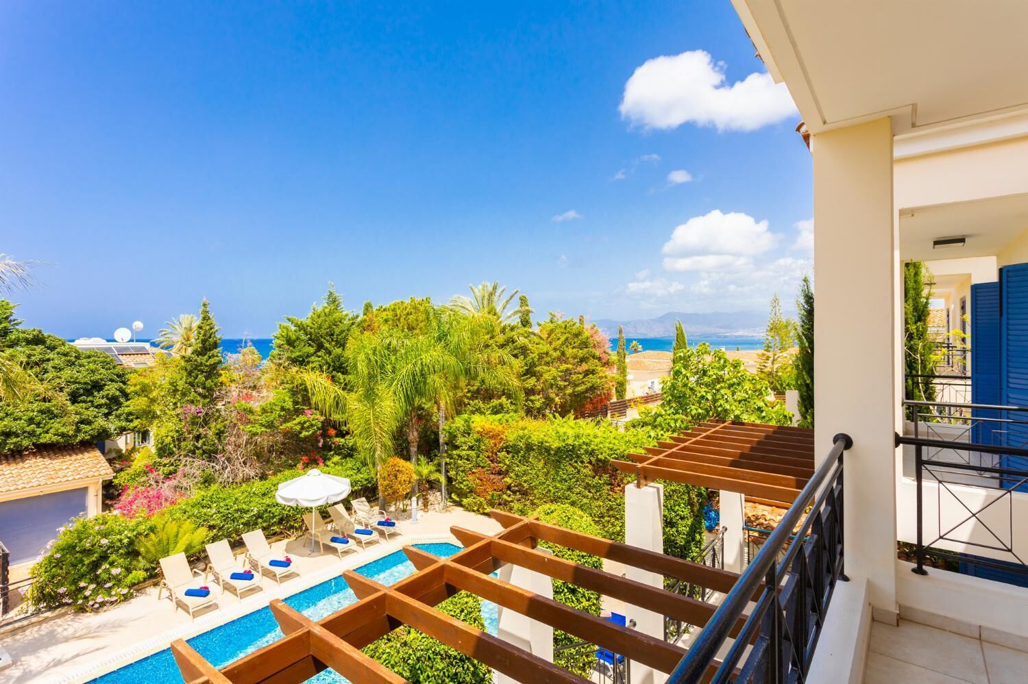 Un balcon avec piscine, donnant sur un jardin luxuriant et la mer.