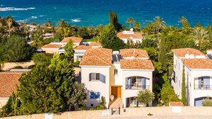 Zona residencial costera con casas de techo de tejas y vistas al océano.