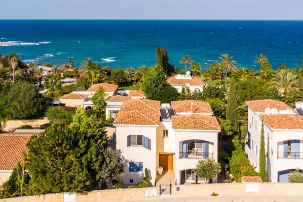Zona residencial costera con casas de techo de tejas y vistas al océano.