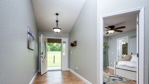 A hallway with a door leading to a bedroom, a ceiling fan, and a view of a grassy yard. -  ✨ 4bed 2.5bath Pool Home. 5 mins from WEC! Sleeps 8-10 Guests. Pet Friendly (Ocala)