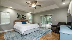 A bedroom with a bed, a ceiling fan, a window with blinds, a painting, and a sliding glass door leading to an outdoor area. -  ✨ 4bed 2.5bath Pool Home. 5 mins from WEC! Sleeps 8-10 Guests. Pet Friendly (Ocala)