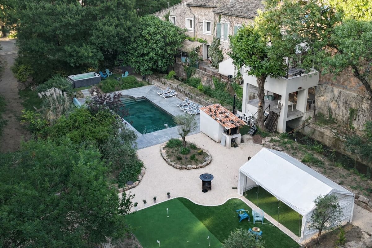An aerial view of a property with a swimming pool, a covered patio, and a garden area.