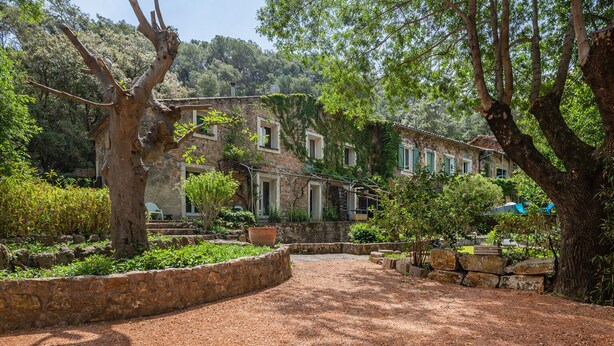 A rustic stone building with a garden pathway leading to a seating area.