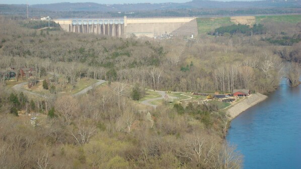 A dam with a water reservoir, a winding road, and a river.