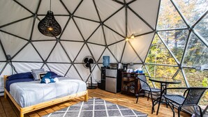 Een gezellig interieur van een geodetische koepel, met een bed, kitchenette en zithoek.