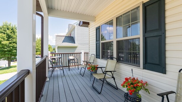 A covered porch with a table and chairs, a potted plant, and a view of a neighboring house. - The Haven, located in the heart of the Shenandoah Valley (Waynesboro)