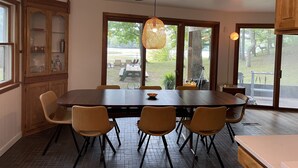 A dining area with a large table, chairs, and a hanging light fixture. - Lakefront Cottage with Private Beach, Sleeps 14 (Newaygo)
