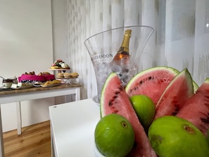 A table with a bottle of champagne, watermelon slices, and lime in a bowl. - Casalinho da Azenha - Charm House (Sintra)