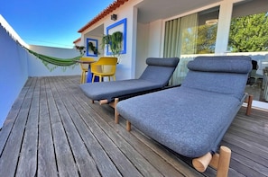 A wooden deck with two lounge chairs and a yellow chair, a hammock, and a table with chairs. - Casalinho da Azenha - Charm House (Sintra)