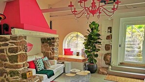 A cozy living room with a stone wall, a red ceiling, and a large window.