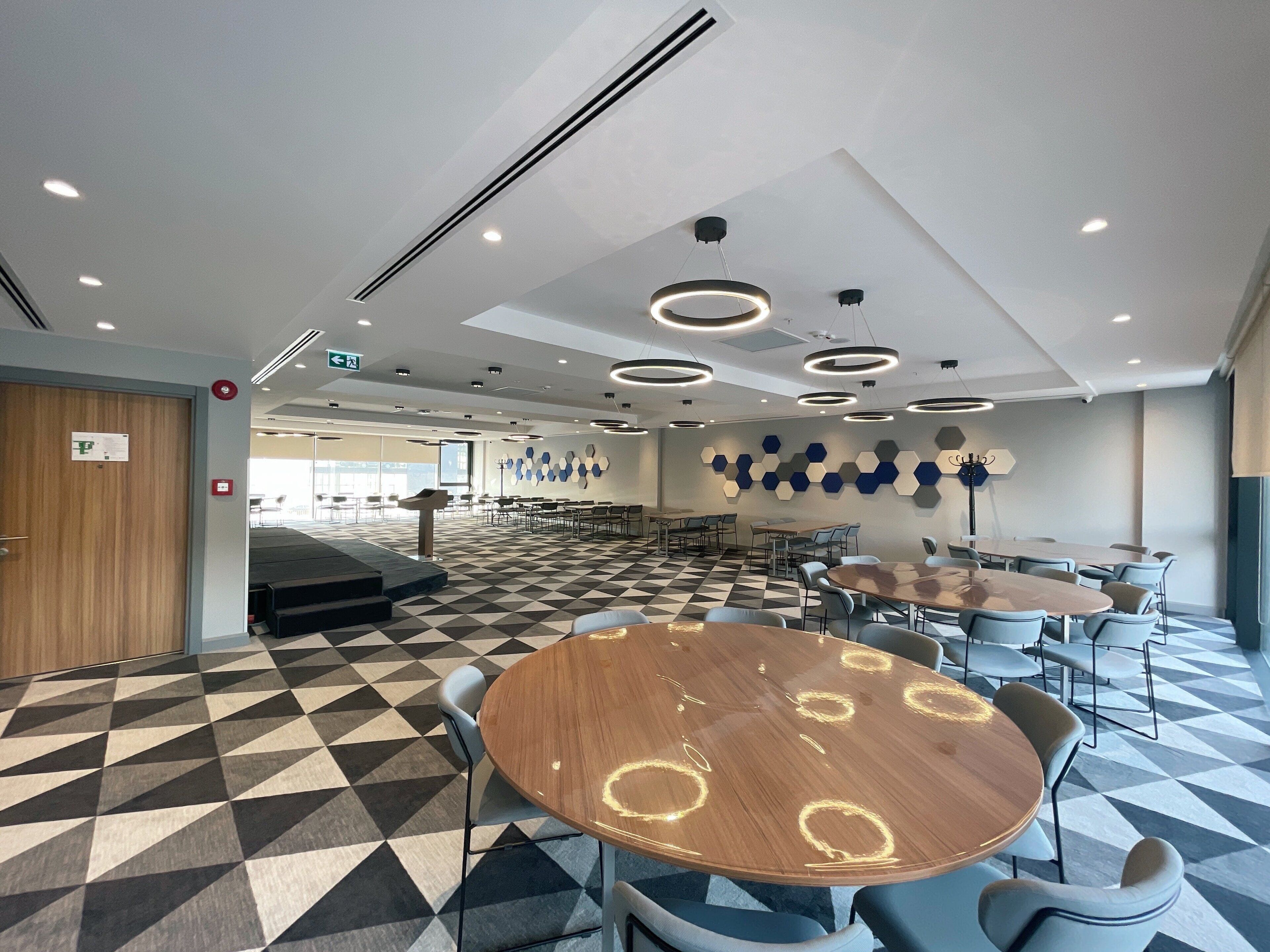 A conference room with a checkered floor, round tables, and chairs.