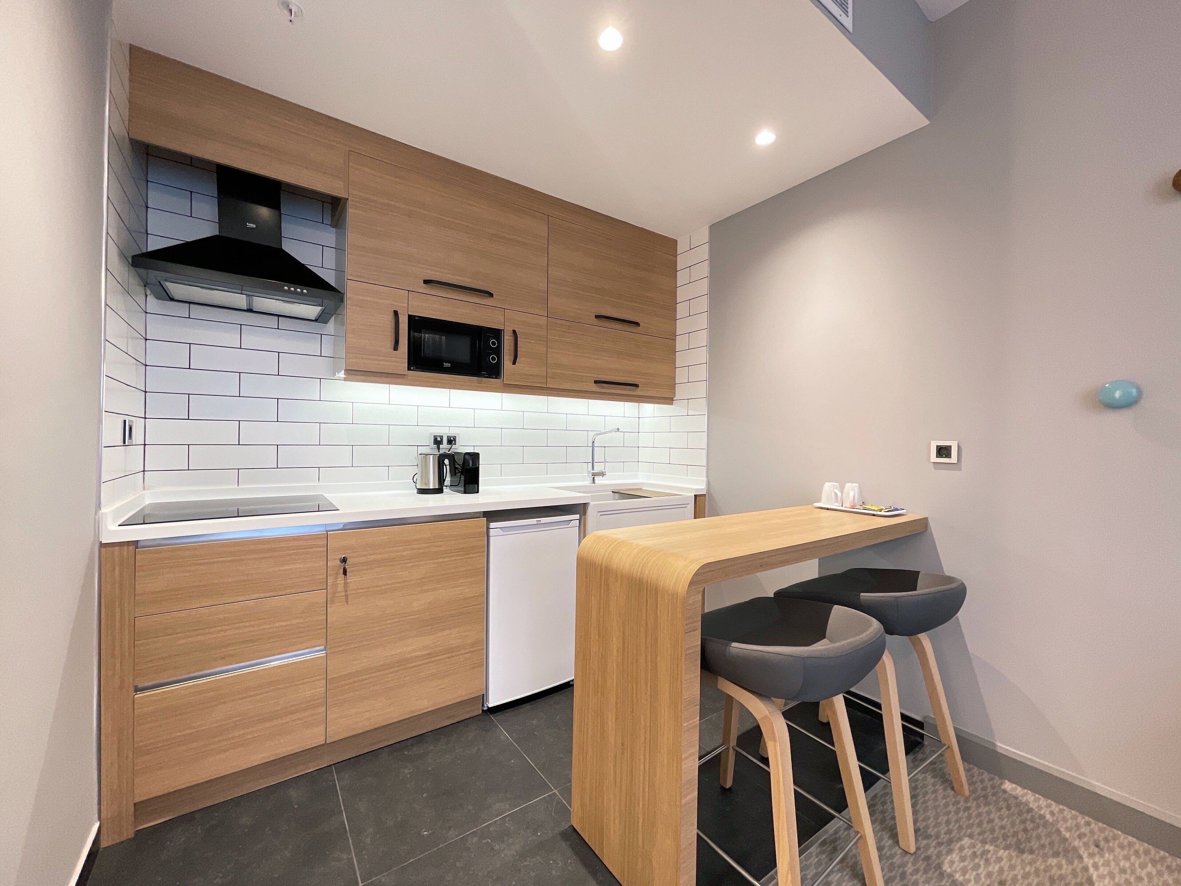 A modern kitchen with wooden cabinets, a microwave, a dishwasher, and a bar area with stools.
