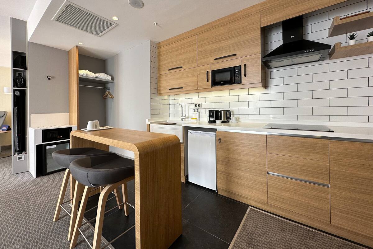 A modern kitchen with wooden cabinets, a microwave, and a coffee maker.