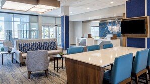 A modern hotel lobby with a large reception desk, seating area, and a large flat-screen TV mounted on the wall. - Holiday Inn Express and Suites Meridian-Boise west by IHG (Meridian)