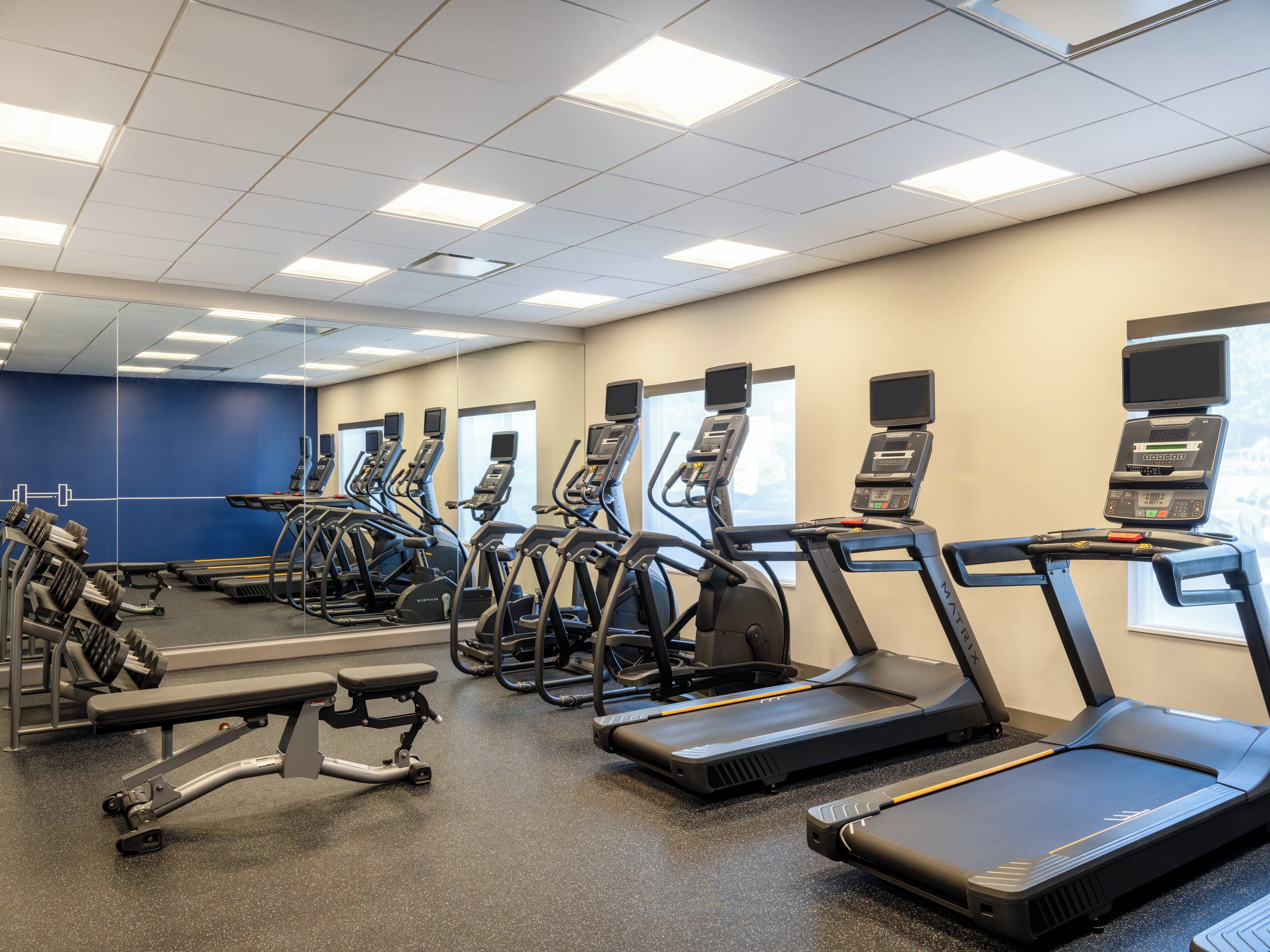 Un gimnasio con cintas de correr, elípticas y máquinas de pesas.