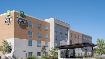 A Holiday Inn Express & Suites hotel with a modern design, featuring a large parking lot and landscaped areas.