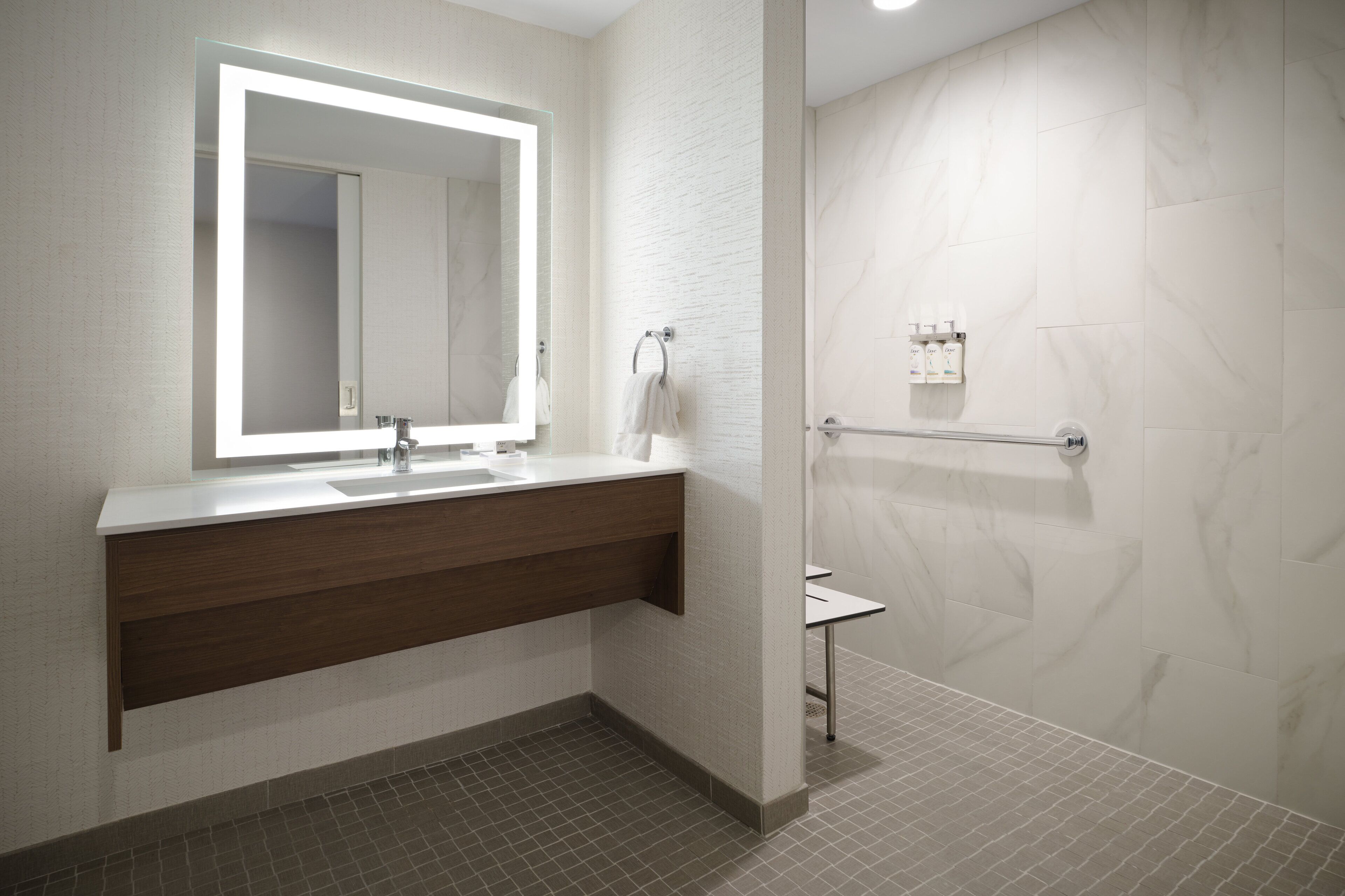 A modern bathroom with a large mirror, a sink, and a shower area.