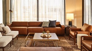 A modern living room with a brown leather sofa, a coffee table, and a side table with a lamp.