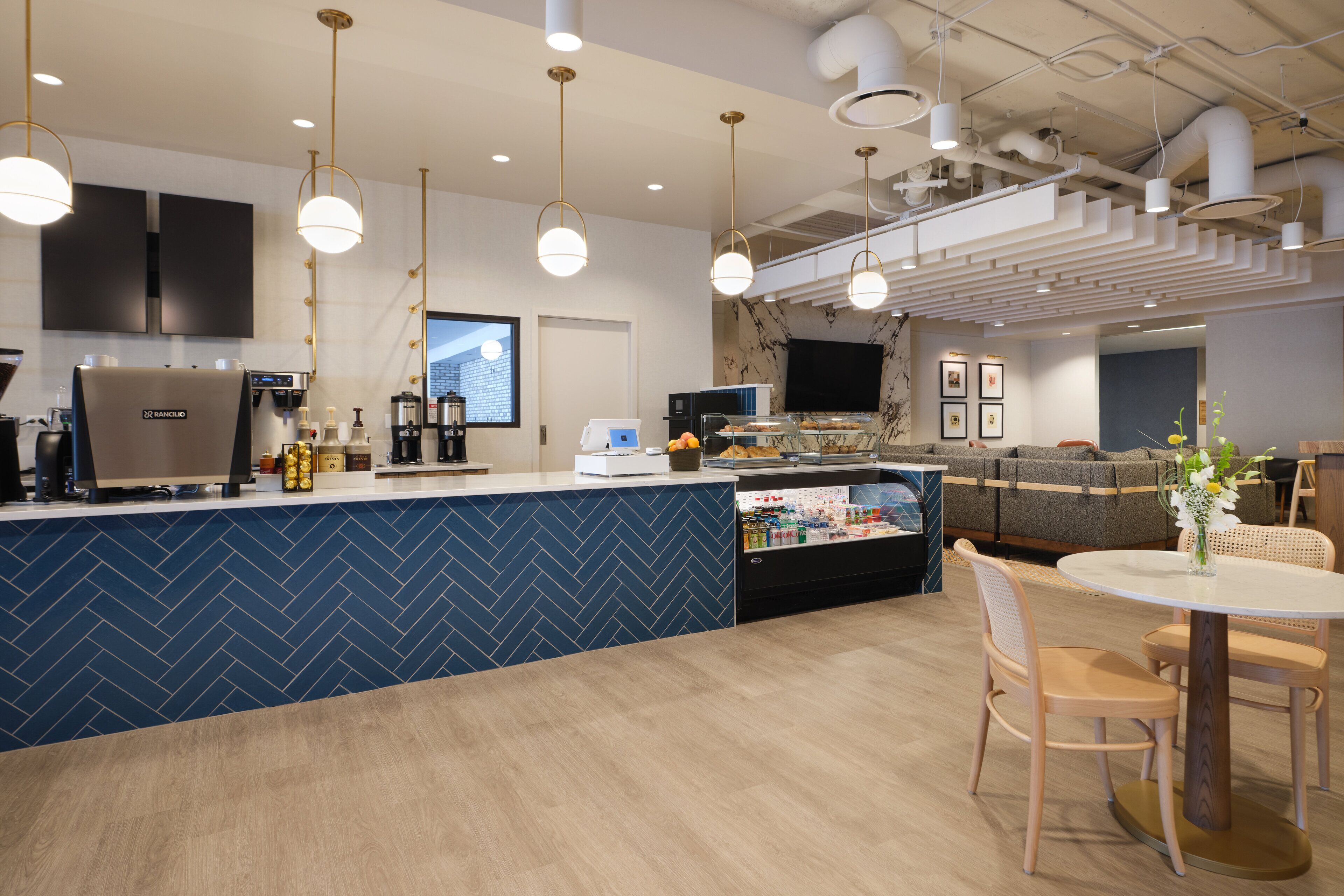 Une cuisine moderne avec un dosseret de carreaux disposés en motif chevron, une machine à café et un réfrigérateur.