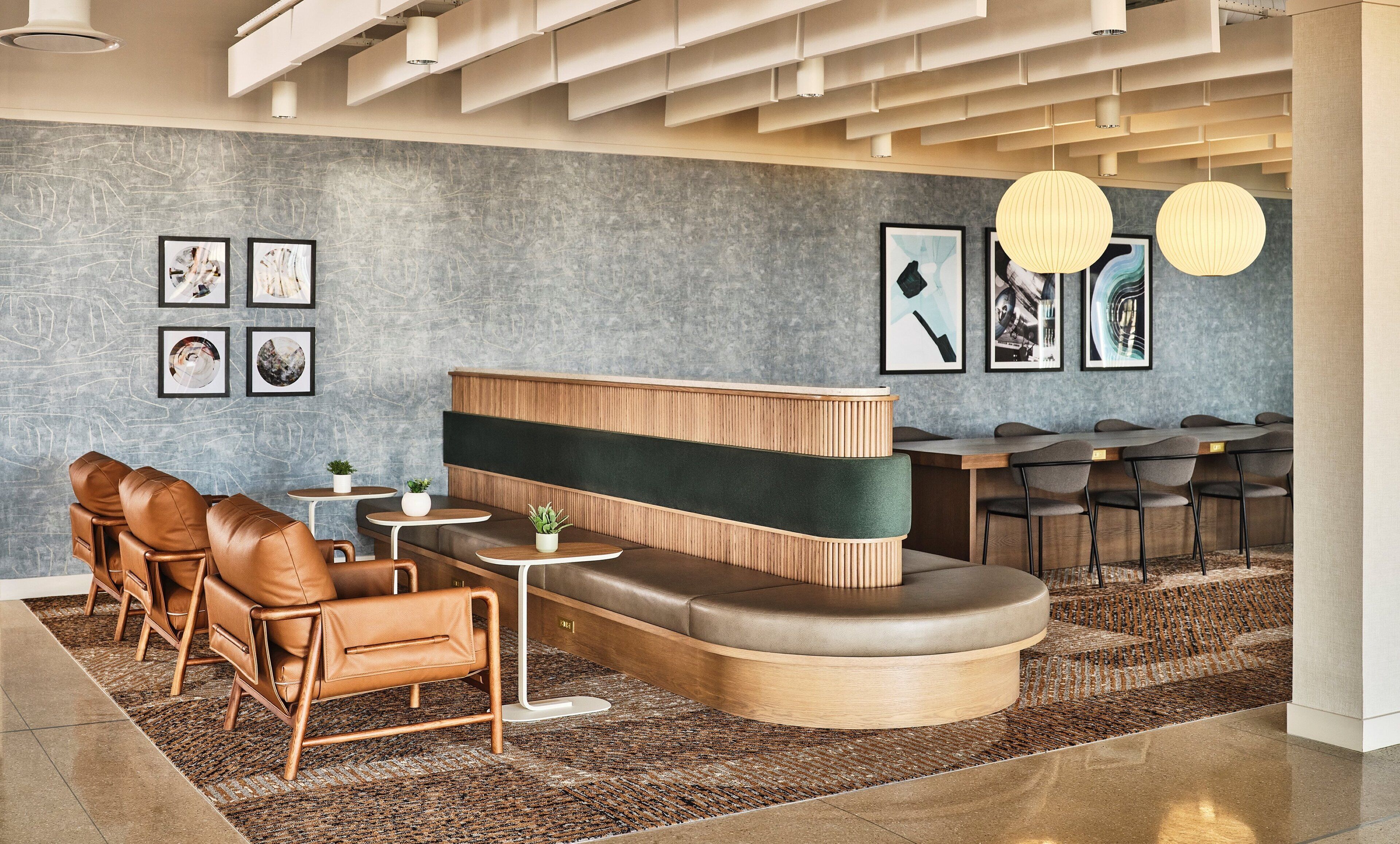 A modern lounge area with leather seating, a wooden reception desk, and a patterned rug.