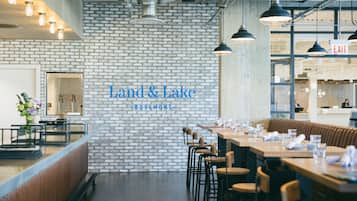 A restaurant interior with a brick wall, wooden tables, and hanging pendant lights.