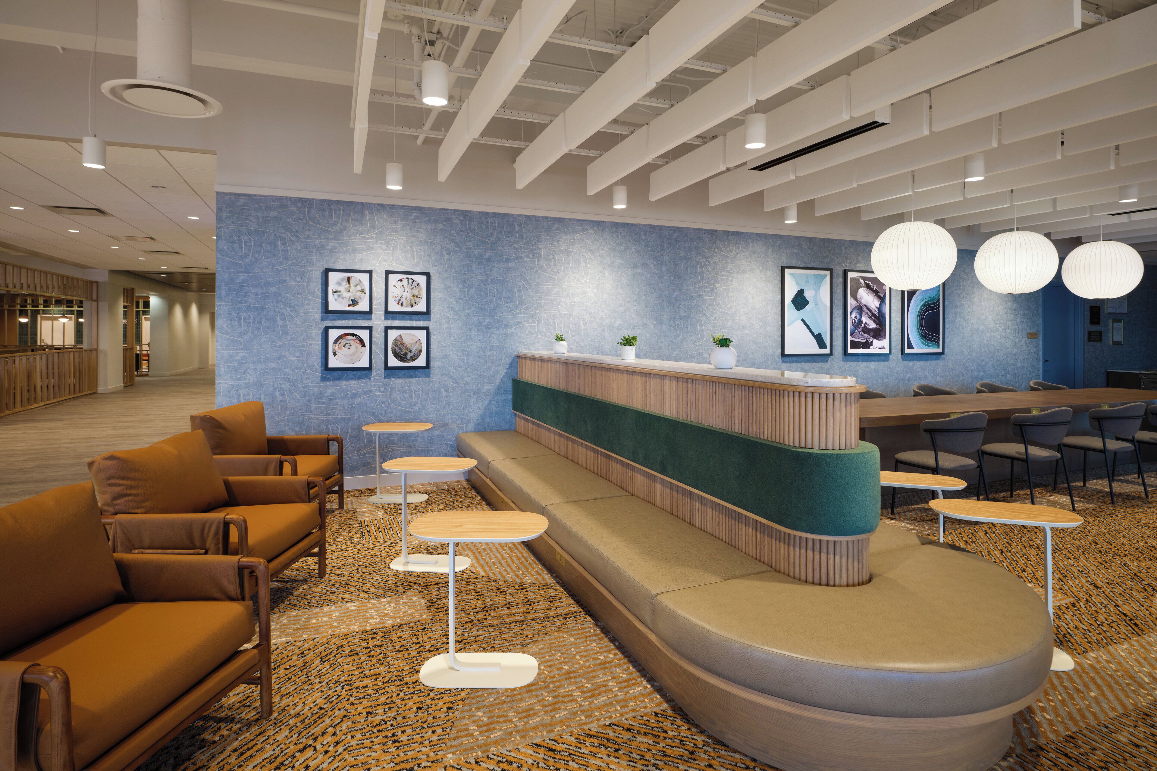 A modern lobby with a reception desk, seating area, and a patterned carpet.