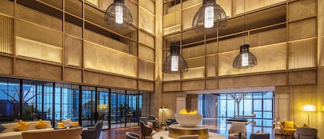 A spacious lobby with high ceilings, large windows, and modern furniture.