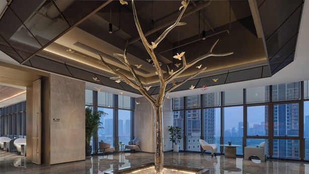A modern lobby with a central tree sculpture, seating areas, and large windows offering city views. - voco Chongqing Chaotianmen by IHG (Chongqing)