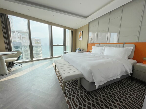 Ein modernes Hotelzimmer mit einem großen Bett, einem Schreibtisch und Blick auf die Stadt.