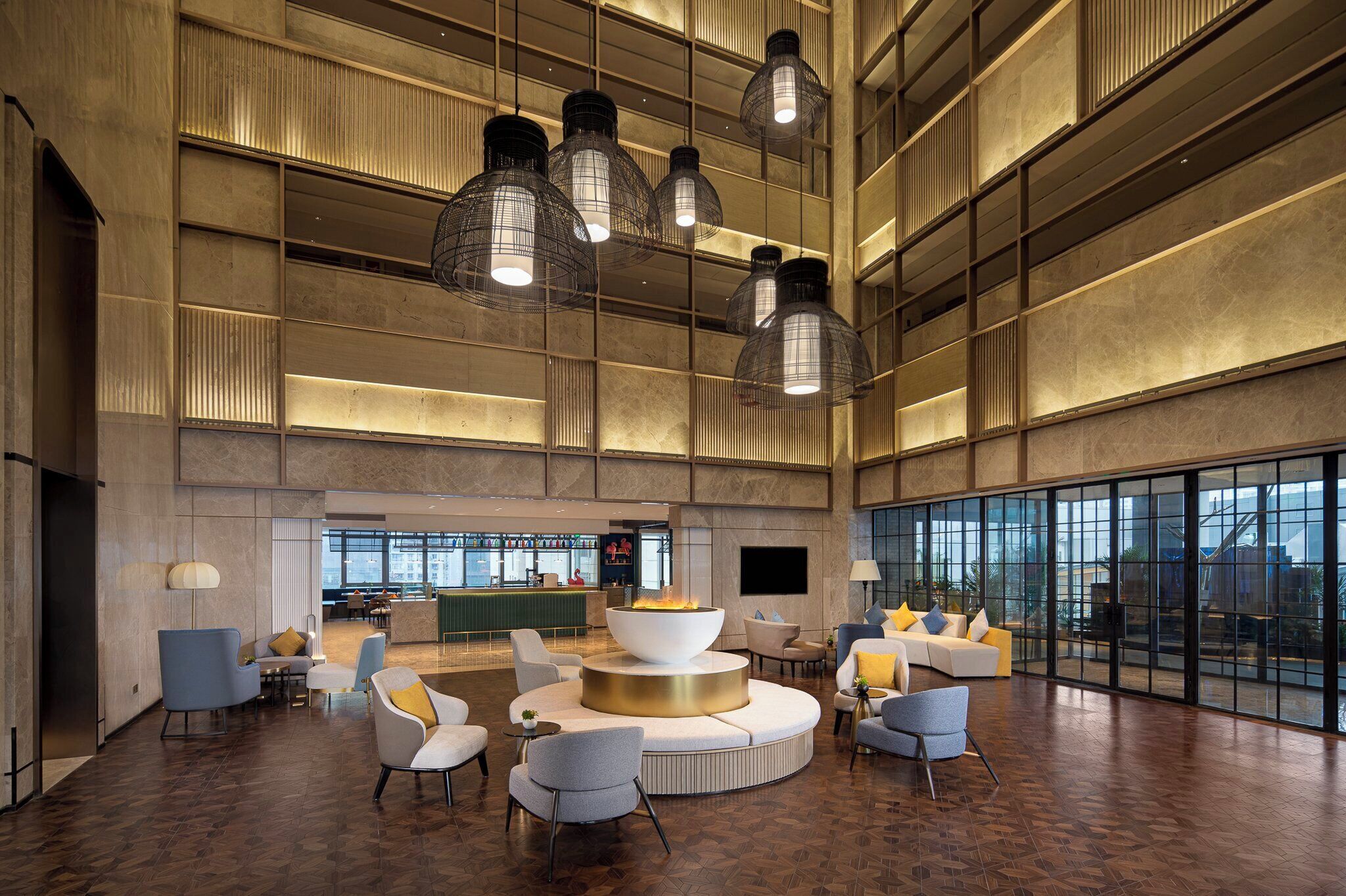 A spacious lobby with a central seating area, a bar, and large windows offering views.