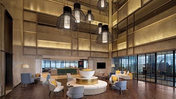 A spacious lobby with a central seating area, a bar, and large windows offering views.