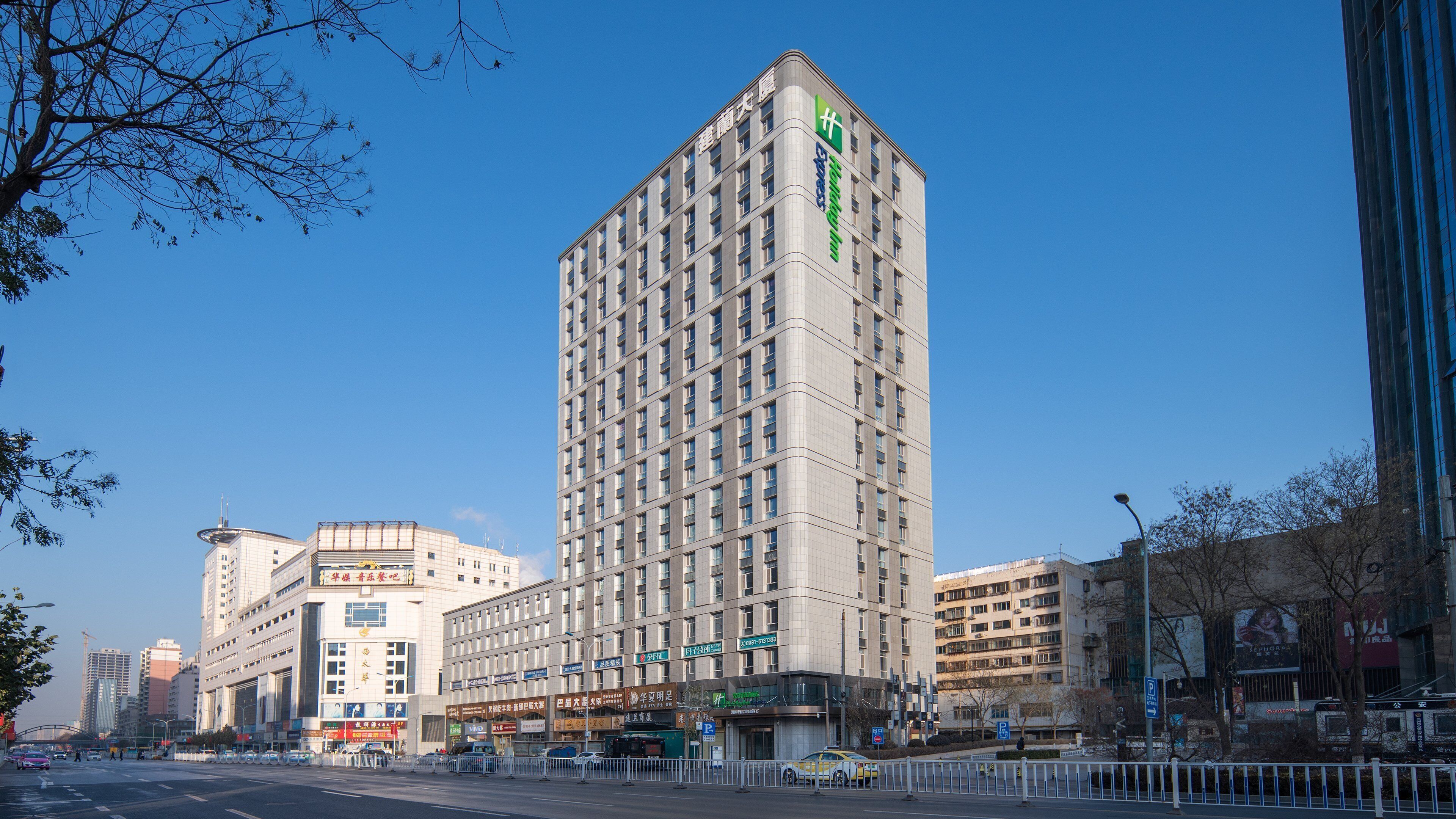 Un grand hôtel au design moderne, reconnaissable à son grand panneau vert placé bien en évidence à l’angle de la rue.