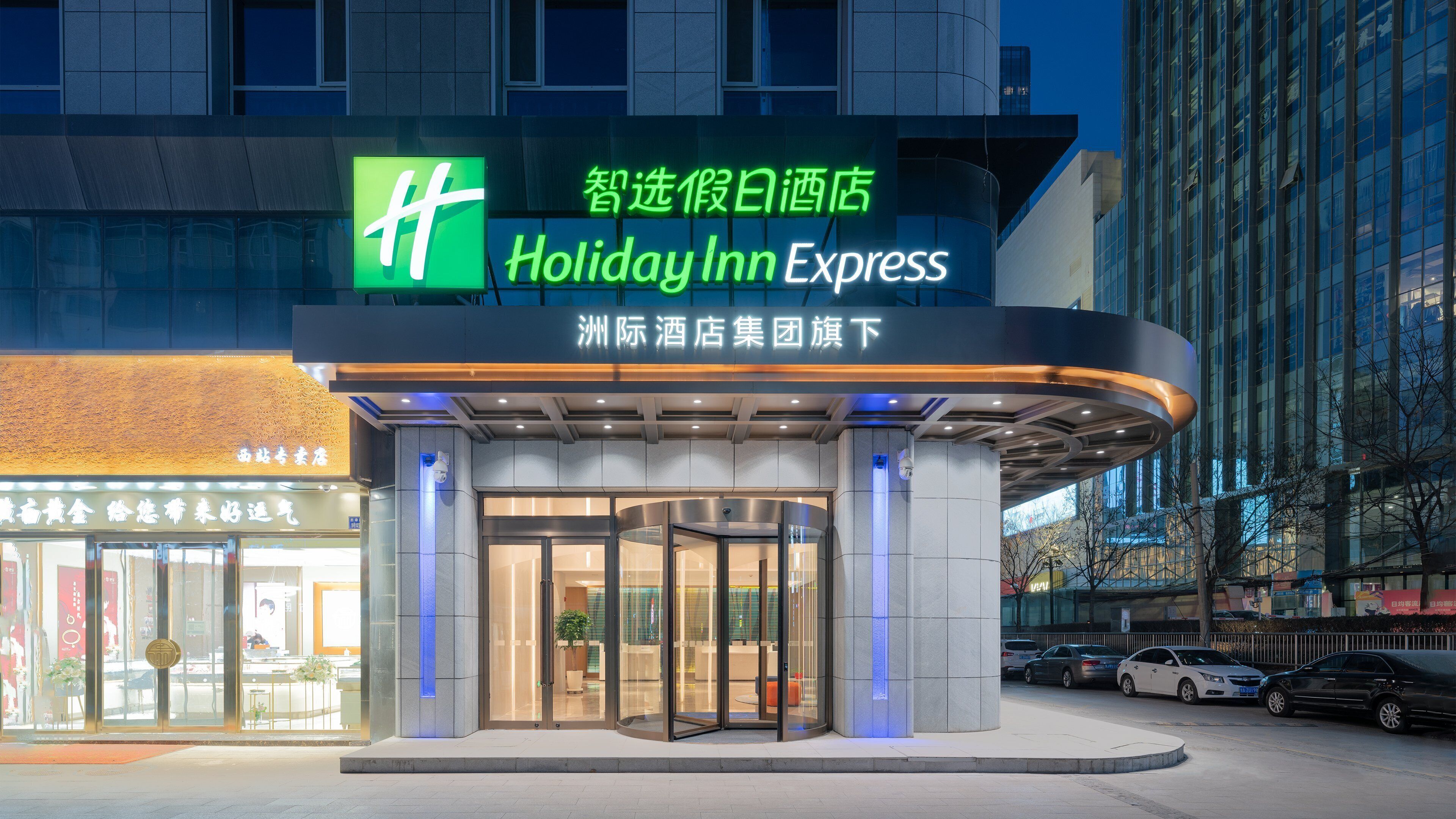 Exterior de un hotel Holiday Inn Express con entrada de vidrio y puerta giratoria.