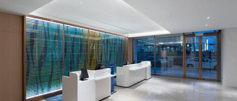 A modern reception area with a glass wall, a reception desk, and a view of the street outside.