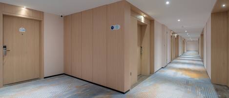 Een hotelgangen met houten deuren, een kamer met een patroon tapijt en een bordje met kamer nummers.