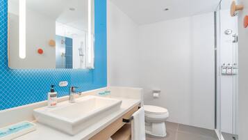 A modern bathroom with a large mirror, two sinks, a toilet, and a shower area.