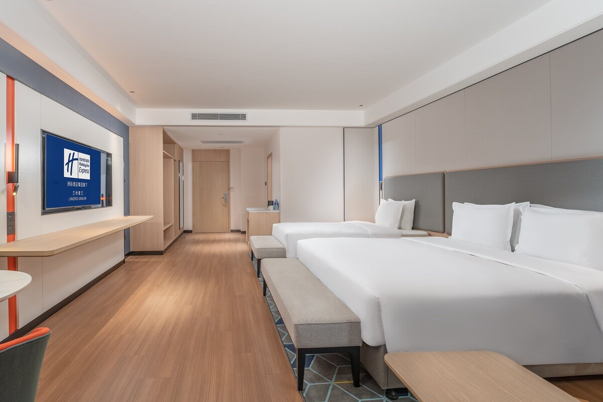 A modern hotel room with a large bed, a desk, and a seating area.