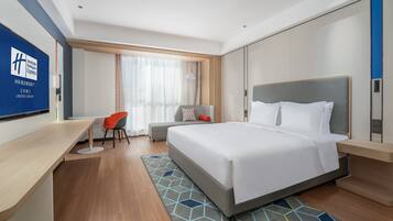 A modern hotel room with a large bed, a desk, and a chair.