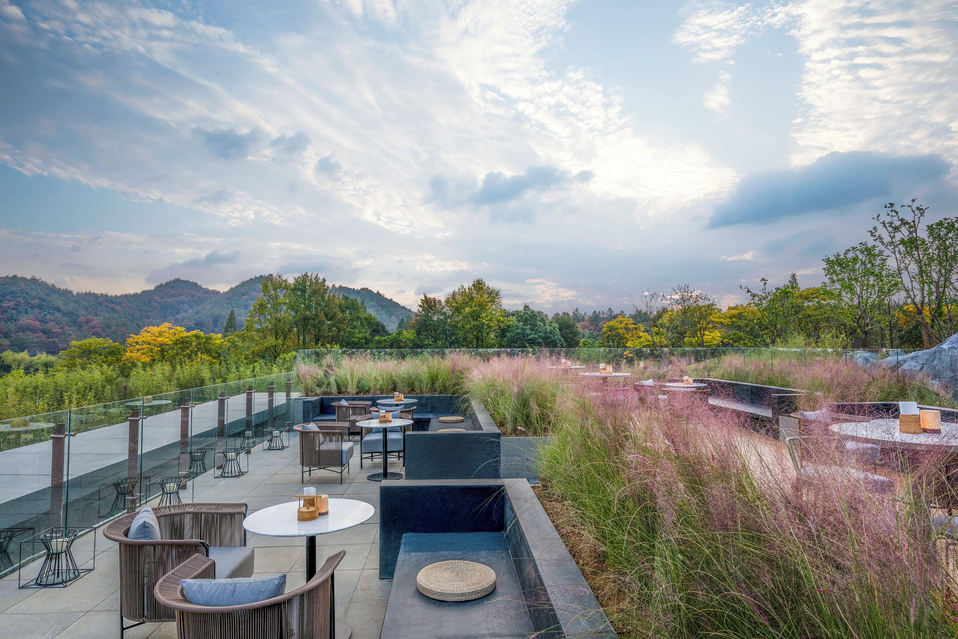 An outdoor terrace with seating and tables, overlooking a mountainous landscape.
