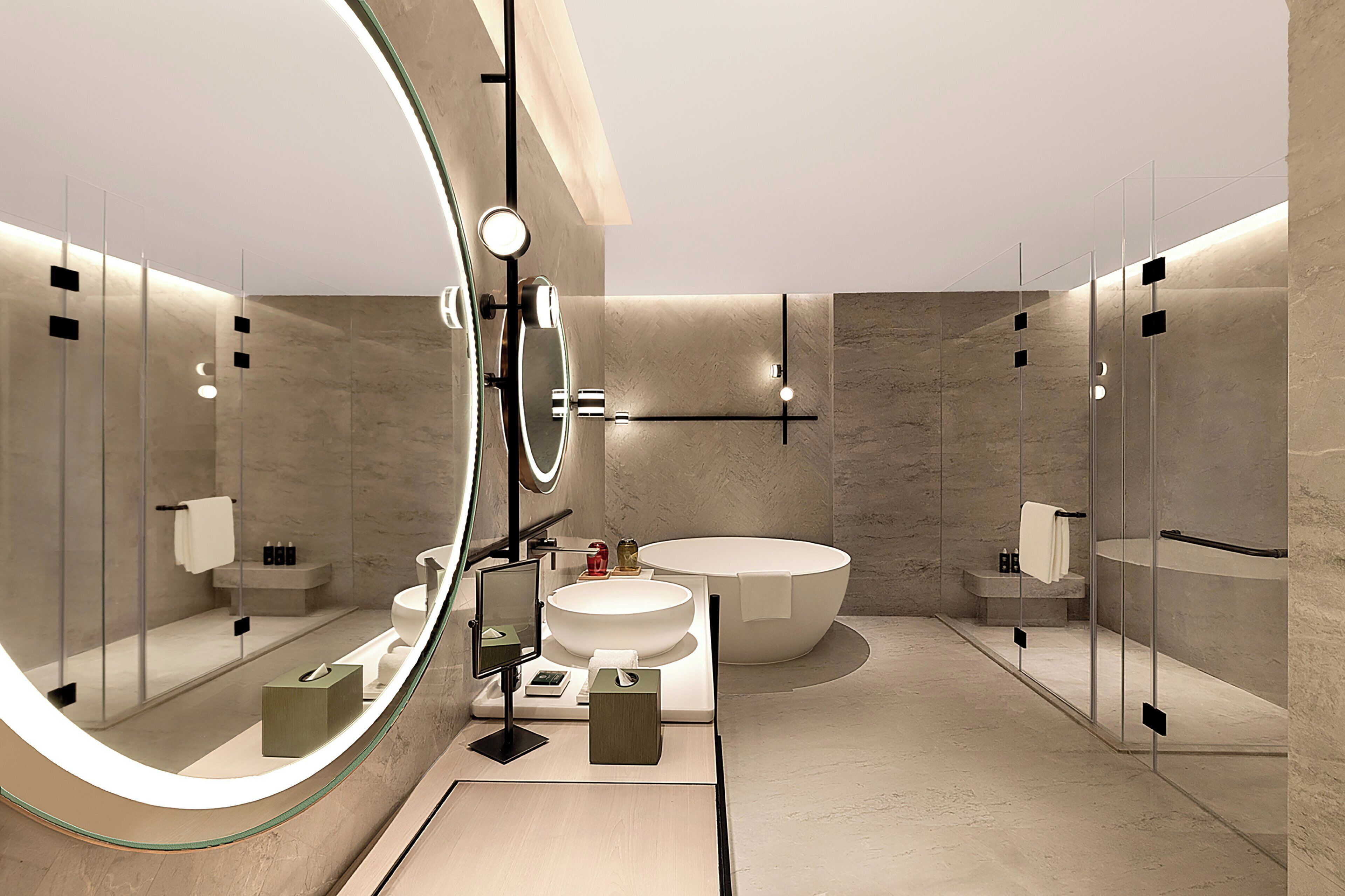 Une salle de bain moderne avec un grand miroir, un lavabo rond, une baignoire sur pieds et une douche séparée par des parois en verre.