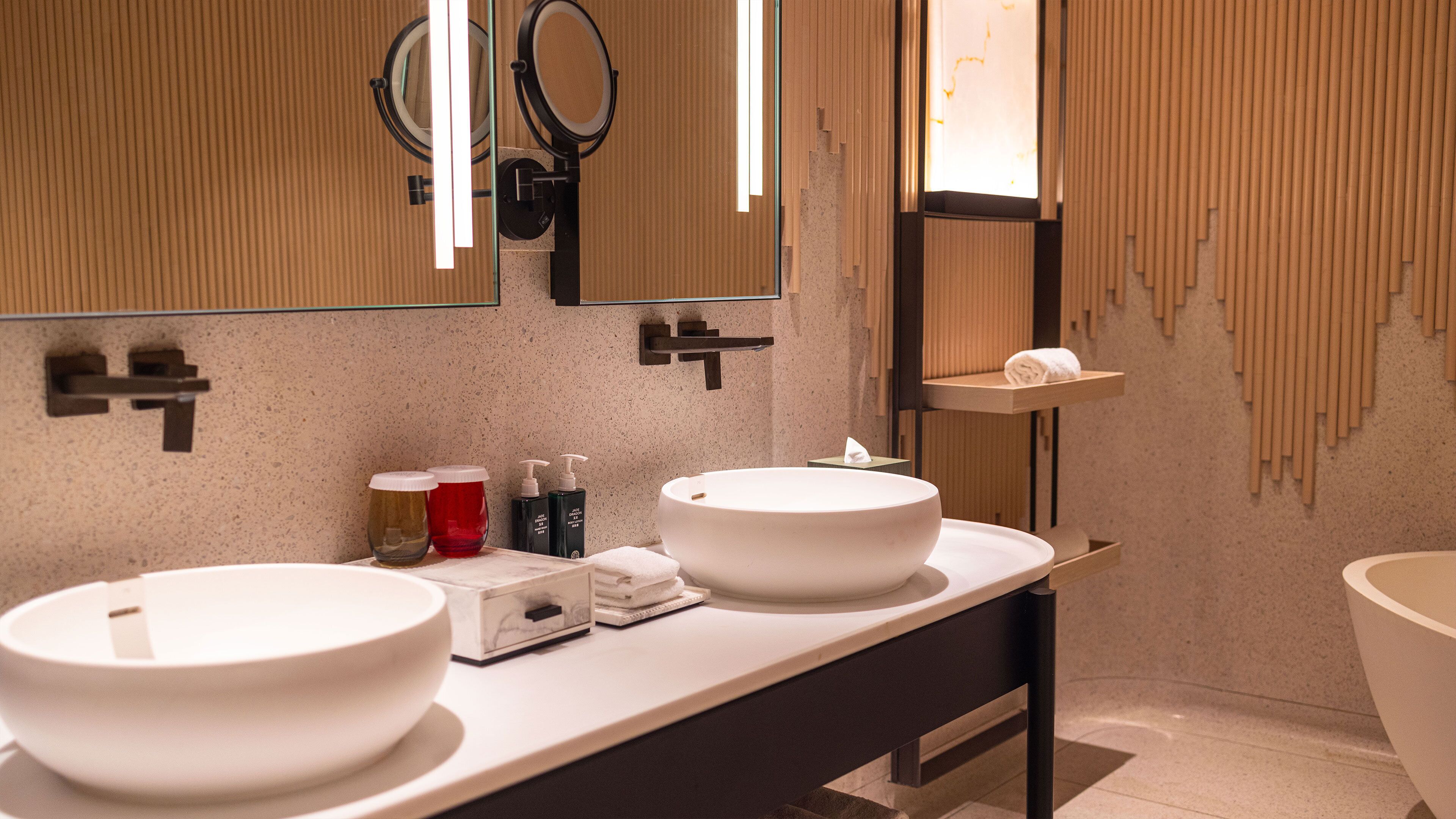 A modern bathroom with two large white sinks, a mirror, and a towel rack.